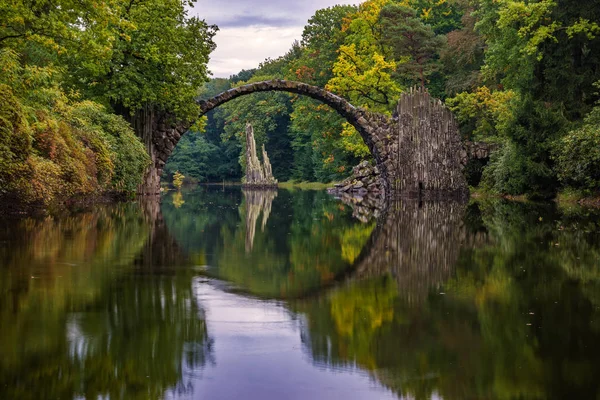 Herbst, bewölkter Abend über der Teufelsbrücke im Park Kromlau, — Stockfoto