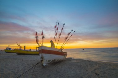 sunset over the sea beach,Fishing boats on the sand clipart