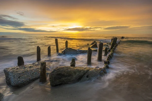 Um quebra-mar que quebra as ondas ao pôr-do-sol — Fotografia de Stock