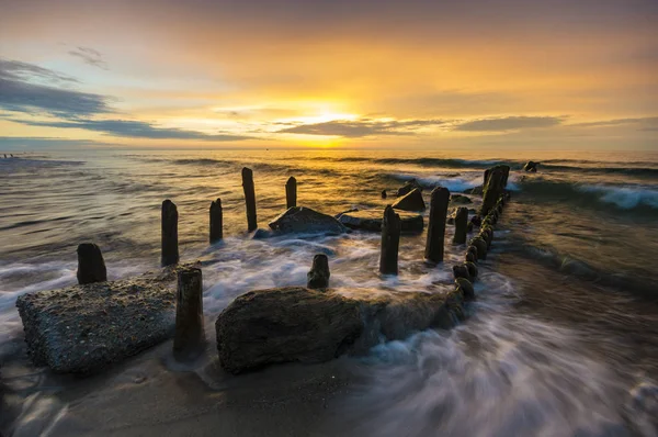 Um quebra-mar que quebra as ondas ao pôr-do-sol — Fotografia de Stock