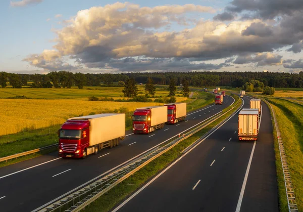 Intensywny ruch drogowy o zachodzie słońca-kolumna ciężarówek na mo — Zdjęcie stockowe