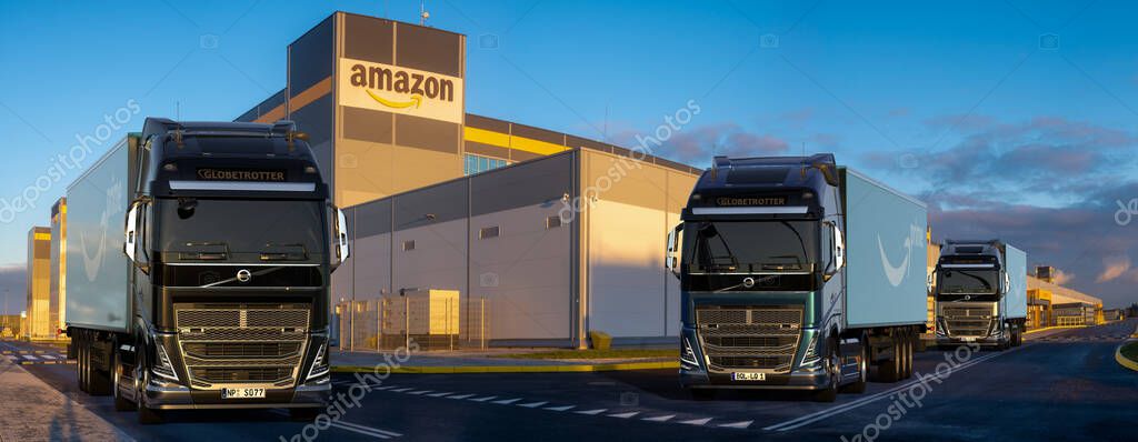 Volvo trucks with trailers with the Amazon logo standing in front of the Amazon logistics center