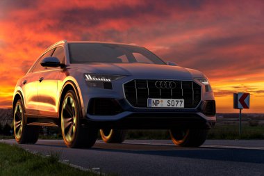 Audi Q8, güzel bir gün batımında yolda lüks bir spor SUV.