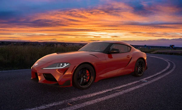 Toyota Supra gün batımından sonra dinamik bir yolda giderken