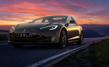 Tesla arabası gün batımı yolunda hareket halinde.