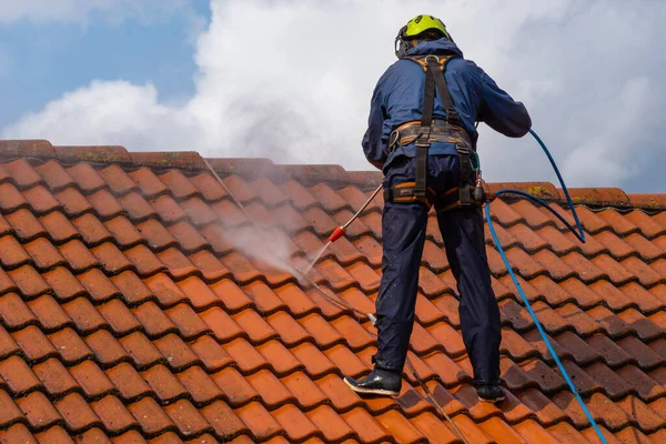 worker washing the roof with pressurized water