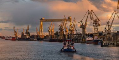 Polonya 'nın Szczecin kentindeki tersanenin üzerindeki batan güneşle aydınlanan güzel fırtına bulutları