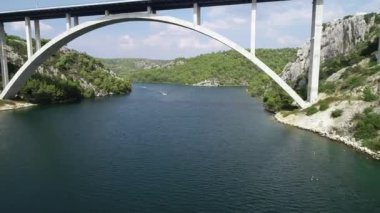 Sibenik Köprüsü 'nün havadan görüntüsü. Hırvatistan, Avrupa 'daki Krka nehri üzerindeki otoban köprüsünün altında uçan insansız hava aracı. Arka planda güzel Akdeniz manzarası, tekneler, yatlar, yelkenliler ve sürat tekneleri.