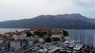 Hırvatistan 'ın Korcula adasının hava manzarası, gün batımında veya gün doğumunda. Kuleleri, marinası, limanı, büyük lüks yatları ve yelkenlileri olan eski bir şehir. Yaz mevsiminde Akdeniz kenti.