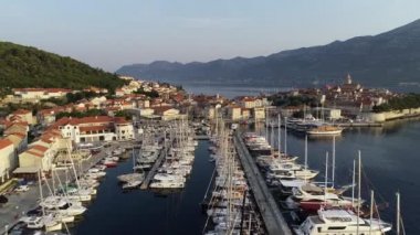 Hırvat körfezi Korcula 'da yelkenli ve yatlı liman manzarası. Dalmaçya şehri, tekneler ve yatlarla dolu körfez boyunca altın gün batımında.. 