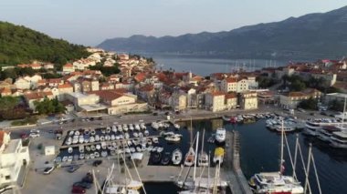 Hırvatistan 'ın Korcula adasının 4K' sındaki hava manzarası. Yaz günü, gün batımında panoramik manzara. Kuleli eski şehir, yelkenli tekneleri ve büyük lüks yatları olan marina.
