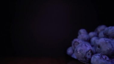 Siyah arkaplanda böğürtlen, böğürtlen, ahududu. Siyah kaselerde taze orman meyveleri. Seçici odaklı, yavaş çekim odaklı sonda mercek dolly alışılmadık görünümü. 