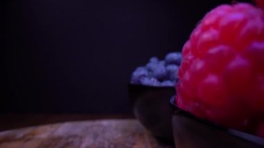 Taze orman meyveleriyle dolu kaseler. Siyah arkaplanda böğürtlen, böğürtlen, ahududu. Seçici odaklı sonda mercek dolly alışılmadık görünümü