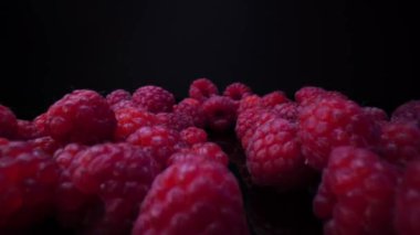 Siyah arka planda ahududu. Yakın plan, manzara. 4K 'de taze, sert ve lezzetli ahududular. Çiğ vejetaryen yaz atıştırmaları, orman meyveleri. Mercek sondası, doli iğnesi.