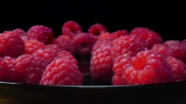 Siyah arka planda ahududu. Yakın plan, manzara. 4K 'de taze, sert ve lezzetli ahududular. Çiğ vejetaryen yaz atıştırmaları, orman meyveleri. Mercek sondası, doli iğnesi.