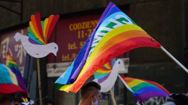 LGBT eşitlik yürüyüşü. Gökkuşağı kıyafetleri ve semboller giyen gençler LGBTQ + hakları için mücadele ediyorlar. Arka planda polis var. Gökkuşağı bayrakları, bayraklar.
