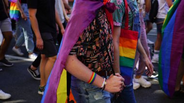 LGBT eşitlik yürüyüşü. Yürüyen gurur yürüyüşü yapan iki eşcinsel. Gökkuşağı kıyafetleri ve semboller giyen gençler LGBTQ + hakları için mücadele ediyorlar. Gökkuşağı bayrakları, bayraklar.