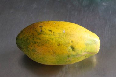 Bütün papaya meyvesi mutfak masasında. Gri metal arkaplan.