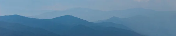 Banner. Blue silhouette of a mountain in the distance, with clouds in the blue sky. Mountains and hills in the distance. Bosnia and Herzegovina.