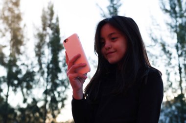 Küçük gülümseyen kız cep telefonu kullanıyor.