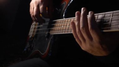Müzisyen Bass Guitar çalıyor. Karanlık arka plan. Yakın çekim.