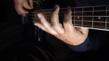 Müzisyen Bass Guitar çalıyor. Karanlık arka plan. Yakın çekim.