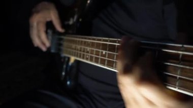 Müzisyen Bass Guitar çalıyor. Karanlık arka plan. Yakın çekim.