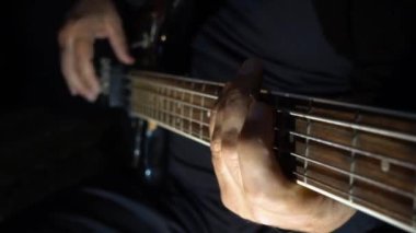 Müzisyen Bass Guitar çalıyor. Karanlık arka plan. Yakın çekim.