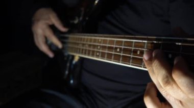Müzisyen Bass Guitar çalıyor. Karanlık arka plan. Yakın çekim.