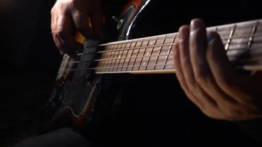 Müzisyen Bass Guitar çalıyor. Karanlık arka plan. Yakın çekim.