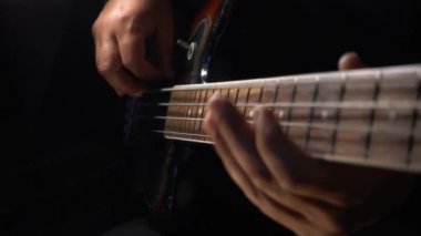 Müzisyen Bass Guitar çalıyor. Karanlık arka plan. Yakın çekim.