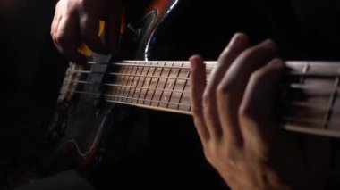 Müzisyen Bass Guitar çalıyor. Karanlık arka plan. Yakın çekim.