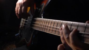 Müzisyen Bass Guitar çalıyor. Karanlık arka plan. Yakın çekim.