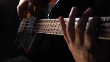 Müzisyen Bass Guitar çalıyor. Karanlık arka plan. Yakın çekim.