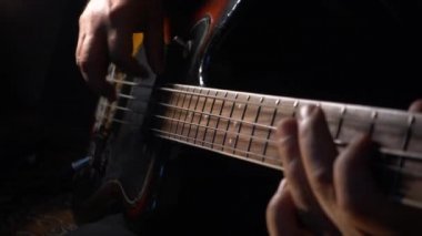 Müzisyen Bass Guitar çalıyor. Karanlık arka plan. Yakın çekim.