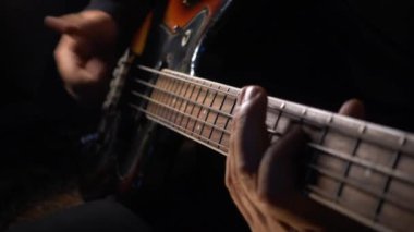 Müzisyen Bass Guitar çalıyor. Karanlık arka plan. Yakın çekim.