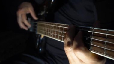 Müzisyen Bass Guitar çalıyor. Karanlık arka plan. Yakın çekim.