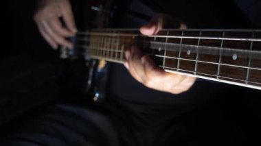 Müzisyen Bass Guitar çalıyor. Karanlık arka plan. Yakın çekim.