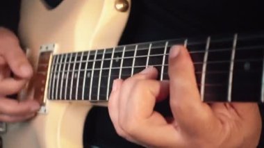 Stüdyoda beyaz gitar çalan müzisyen.