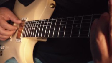 Stüdyoda beyaz gitar çalan müzisyen.