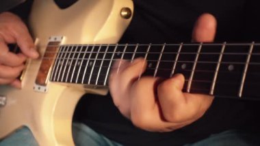 Stüdyoda beyaz gitar çalan müzisyen.