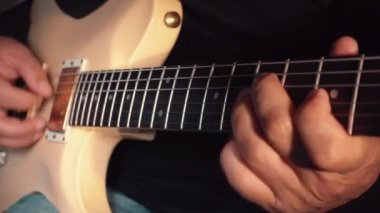 Stüdyoda beyaz gitar çalan müzisyen.