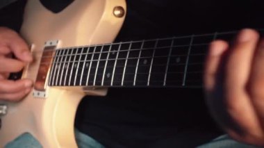 Stüdyoda beyaz gitar çalan müzisyen.