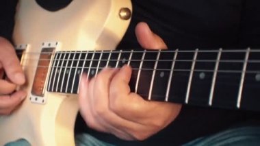 Stüdyoda beyaz gitar çalan müzisyen.