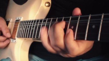 Stüdyoda beyaz gitar çalan müzisyen.