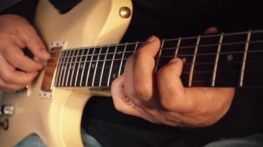 Stüdyoda beyaz gitar çalan müzisyen.