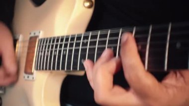 Stüdyoda beyaz gitar çalan müzisyen.