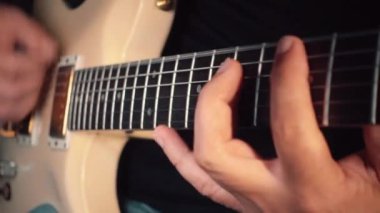 Stüdyoda beyaz gitar çalan müzisyen.