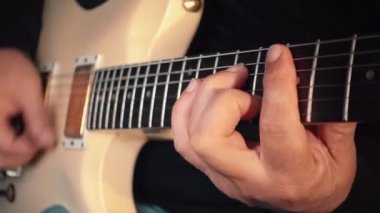 Stüdyoda beyaz gitar çalan müzisyen.