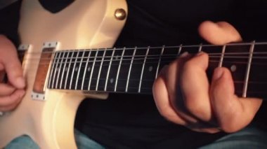 Stüdyoda beyaz gitar çalan müzisyen.